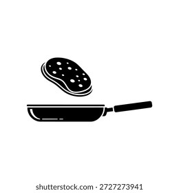 A pancake being flipped in a frying pan, illustrating cooking and breakfast preparation.