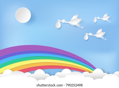 Paper art of stork flying with baby and rainbow on blue sky paper cut style illustration