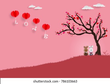 Paper art Vector illustration of couple white and brown rabbits sitting on red grass under tree of love while looking at the LOVE alphabet balloons on sky with pink background for valentine festival.