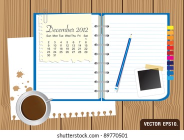 Paper and blue Notebook With a cup of coffee and photo frame. on brown wood background. Calendar 2012 December Vector template for design work