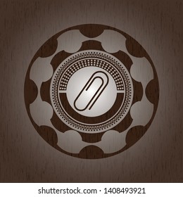 paper clip icon inside badge with wood background