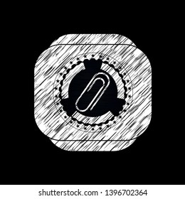 paper clip icon inside chalkboard emblem on black board