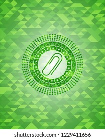 paper clip icon inside green emblem with triangle mosaic background