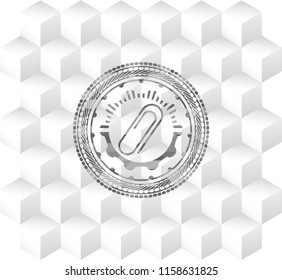 paper clip icon inside grey emblem with geometric cube white background