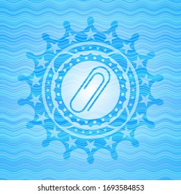 paper clip icon inside sky blue water wave emblem.