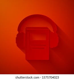 Paper cut Audio book icon isolated on red background. Book with headphones. Audio guide sign. Online learning concept. Paper art style. Vector Illustration