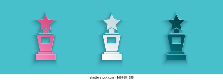 Paper cut Award cup icon isolated on blue background. Winner trophy symbol. Championship or competition trophy. Sports achievement sign. Paper art style. Vector Illustration