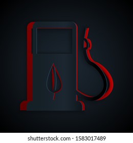Paper cut Bio fuel concept with fueling nozzle and leaf icon isolated on black background. Gas station with leaves. Eco refueling. Paper art style. Vector Illustration
