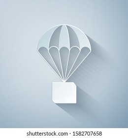 Paper cut Box flying on parachute icon isolated on grey background. Parcel with parachute for shipping. Delivery service, air shipping concept, bonus concept. Paper art style. Vector Illustration