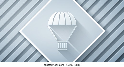 Paper cut Box flying on parachute icon isolated on grey background. Parcel with parachute for shipping. Delivery service, air shipping. Paper art style. Vector Illustration