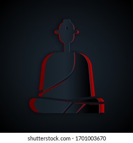 Paper cut Buddhist monk in robes sitting in meditation icon isolated on black background. Paper art style. Vector Illustration