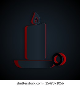Paper cut Burning candle in candlestick icon isolated on black background. Old fashioned lit candle. Cylindrical candle stick with burning flame. Paper art style. Vector Illustration