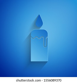 Paper cut Burning candle in candlestick icon isolated on blue background. Cylindrical candle stick with burning flame. Paper art style. Vector Illustration