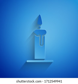 Paper cut Burning candle in candlestick icon isolated on blue background. Cylindrical candle stick with burning flame. Paper art style. Vector Illustration
