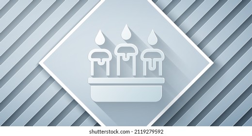 Paper cut Burning candle in candlestick icon isolated on grey background. Cylindrical candle stick with burning flame. Paper art style. Vector