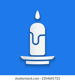 Paper cut Burning candle icon isolated on blue background. Cylindrical candle stick with burning flame. Paper art style. Vector Illustration