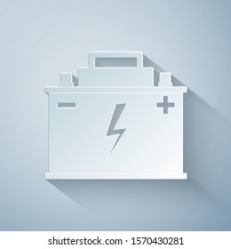 Paper cut Car battery icon isolated on grey background. Accumulator battery energy power and electricity accumulator battery. Lightning bolt symbol. Paper art style. Vector Illustration