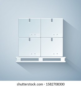 Paper cut Cardboard boxes on pallet icon isolated on grey background. Closed carton delivery packaging box with fragile signs. Paper art style. Vector Illustration