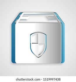 Paper cut Delivery pack security symbol with shield icon isolated on grey background. Delivery insurance. Insured cardboard boxes beyond the shield. Paper art style. Vector Illustration