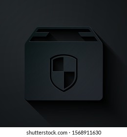 Paper cut Delivery pack security symbol with shield icon isolated on black background. Delivery insurance. Insured cardboard boxes beyond the shield. Paper art style. Vector Illustration