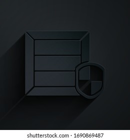 Paper cut Delivery pack security with shield icon isolated on black background. Delivery insurance. Insured cardboard boxes beyond the shield. Paper art style. Vector Illustration