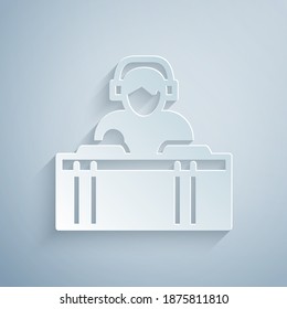 Paper cut DJ wearing headphones in front of record decks icon isolated on grey background. DJ playing music. Paper art style. Vector.