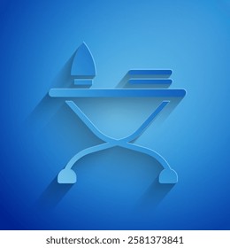 Paper cut Electric iron and ironing board icon isolated on blue background. Steam iron. Paper art style. Vector