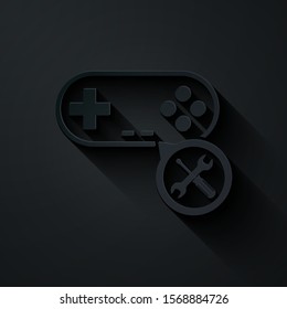 Paper cut Gamepad with screwdriver and wrench icon isolated on black background. Adjusting, service, setting, maintenance, repair, fixing. Paper art style. Vector Illustration