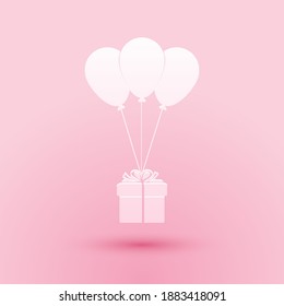 Paper cut Gift box with balloons icon isolated on pink background. Paper art style. Vector.