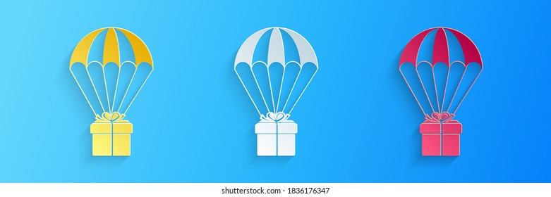 Caja de regalo de corte de papel volando sobre icono de paracaídas aislado en fondo azul. Servicio de entrega, concepto de transporte aéreo, concepto de bonificación. Estilo de arte de papel. Vector.