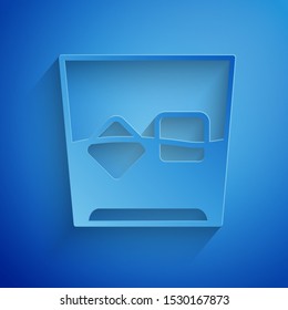 Paper cut Glass of whiskey and ice cubes icon isolated on blue background. Paper art style. Vector Illustration