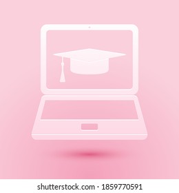 Paper cut Graduation cap and laptop icon isolated on pink background. Online learning or e-learning concept icon. Paper art style. Vector.