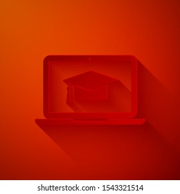 Paper cut Graduation cap on screen laptop icon isolated on red background. Online learning or e-learning concept. Paper art style. Vector Illustration