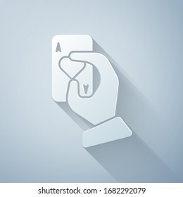 Paper cut Hand holding playing cards icon isolated on grey background. Casino game design. Paper art style. Vector Illustration
