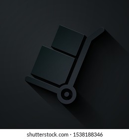 Paper cut Hand truck and boxes icon isolated on black background. Dolly symbol. Paper art style. Vector Illustration