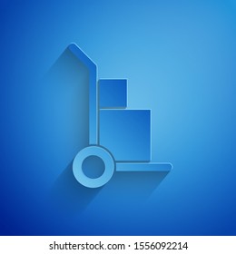 Paper cut Hand truck and boxes icon isolated on blue background. Dolly symbol. Paper art style. Vector Illustration