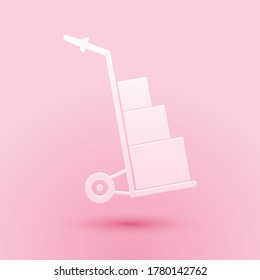 Paper cut Hand truck and boxes icon isolated on pink background. Dolly symbol. Paper art style. Vector