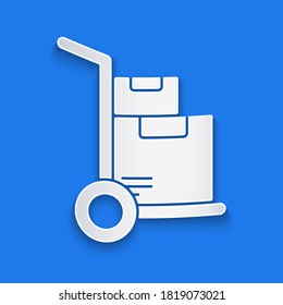 Paper cut Hand truck and boxes icon isolated on blue background. Dolly symbol. Paper art style. Vector Illustration