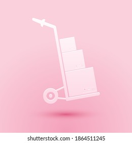 Paper cut Hand truck and boxes icon isolated on pink background. Dolly symbol. Paper art style. Vector.