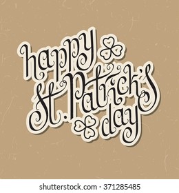Paper cut hand written St. Patrick's day greetings over textured vintage brown background.