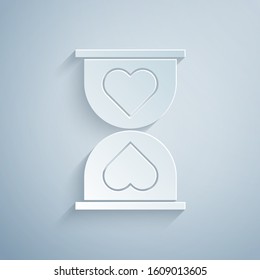 Paper cut Heart in the center old hourglass icon isolated on grey background. Valentines day. Paper art style. Vector Illustration