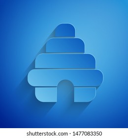 Paper cut Hive for bees icon isolated on blue background. Beehive symbol. Apiary and beekeeping. Sweet natural food. Paper art style. Vector Illustration