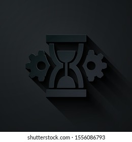 Paper cut Hourglass and gear icon isolated on black background. Time Management symbol. Clock and gear icon. Productivity symbol. Paper art style. Vector Illustration