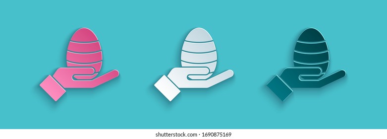 Paper cut Human hand and easter egg icon isolated on blue background. Happy Easter. Paper art style. Vector Illustration