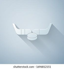 Paper cut Ice hockey sticks and puck icon isolated on grey background. Game start. Paper art style. Vector Illustration