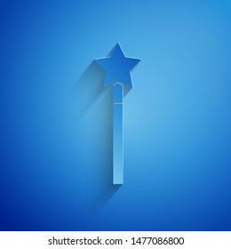 Paper cut Magic wand icon isolated on blue background. Star shape magic accessory. Magical power. Paper art style. Vector Illustration