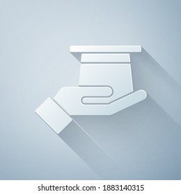 Paper cut Magician hat in hand icon isolated on grey background. Magic trick. Mystery entertainment concept. Paper art style. Vector