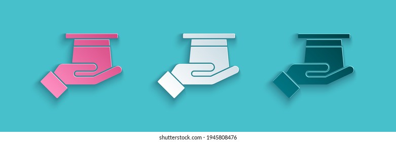 Paper cut Magician hat in hand icon isolated on blue background. Magic trick. Mystery entertainment concept. Paper art style. Vector