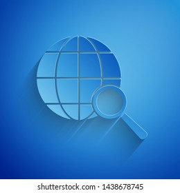 Paper cut Magnifying glass with globe icon isolated on blue background. Analyzing the world. Global search sign. Paper art style. Vector Illustration