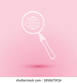 Paper cut Magnifying glass with globe icon isolated on pink background. Analyzing the world. Global search sign. Paper art style. Vector.